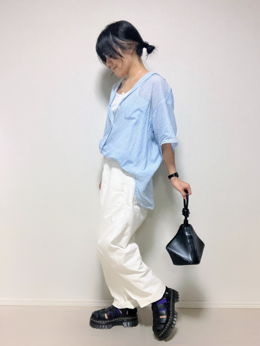 ブルー系のシャツ/ブラウス、ブラック系のハンドバッグ、ブラック系のサンダルを着用したレディースの夏コーディネートの2枚目の写真