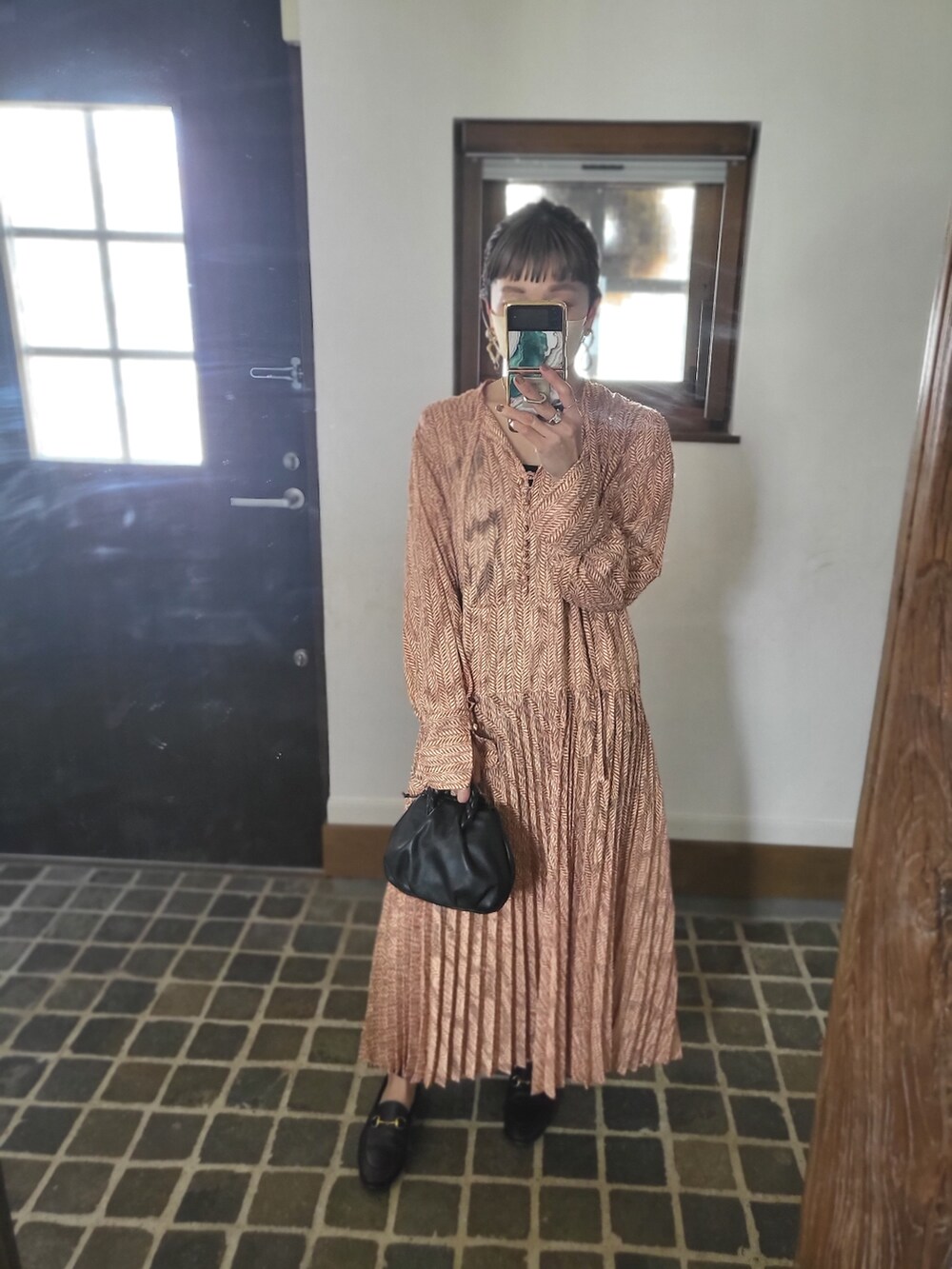 オレンジ系のワンピース/ドレス、ブラック系のショルダーバッグ、ブラック系のローファーを着用したレディースの春コーディネートの2枚目の写真