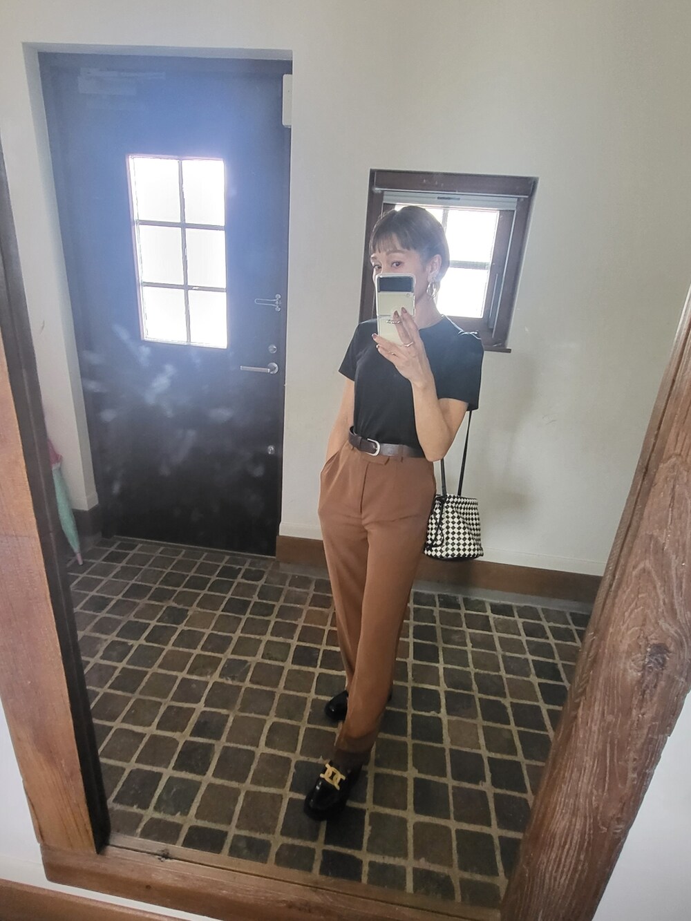 ブラック系のTシャツ/カットソー、ブラック系のショルダーバッグ、ブラウン系のスラックスを着用したレディースの秋コーディネートの2枚目の写真