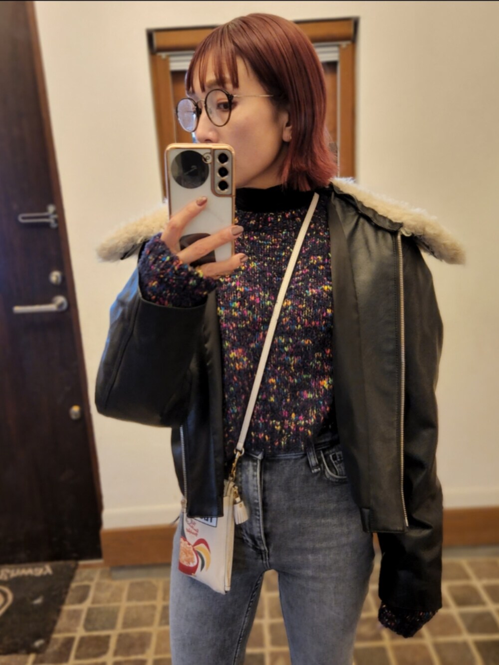 ブラック系のライダースジャケット、ブルー系のニット/セーター、グレー系のデニムパンツを着用したレディースの冬コーディネートの2枚目の写真