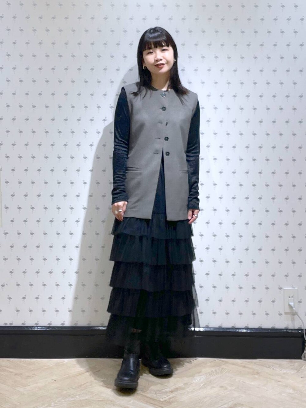 ブラック系のTシャツ/カットソー、グレー系のベスト、ブラック系のスカートを着用したレディースの冬コーディネートの2枚目の写真