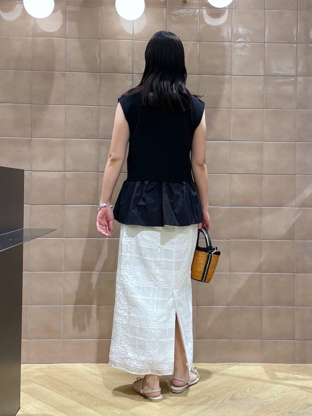 ブラック系のベスト、ブラック系のショルダーバッグ、ホワイト系のサンダルを着用したレディースの春コーディネートの3枚目の写真