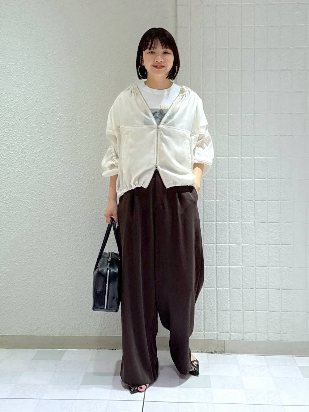 ブラック系のボストンバッグ、ホワイト系のブルゾン、ブラック系のサンダルを着用したレディースの春コーディネートの2枚目の写真