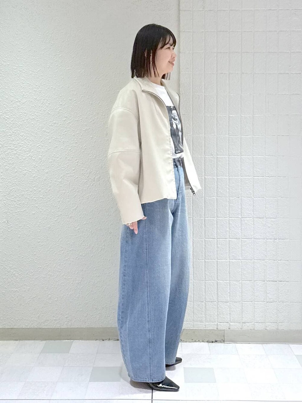 ブルー系のデニムパンツ、ホワイト系のブルゾン、ブラック系のパンプスを着用したレディースの春コーディネートの3枚目の写真