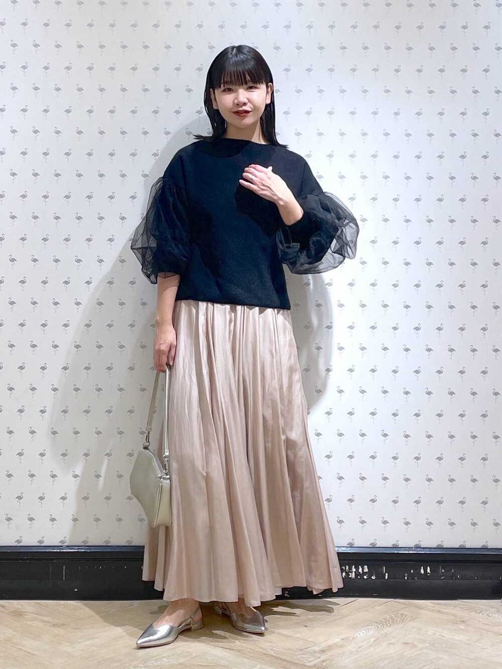 シルバー系のショルダーバッグ、ベージュ系のスカート、シルバー系のパンプスを着用したレディースの冬コーディネートの3枚目の写真