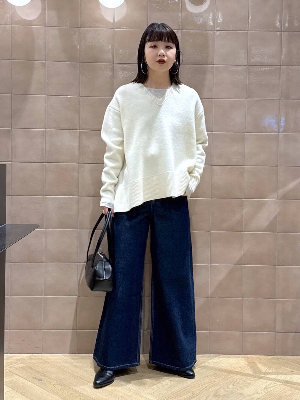 ホワイト系のニット/セーター、グレー系のTシャツ/カットソー、ブラック系のブーツを着用したレディースの冬コーディネートの2枚目の写真