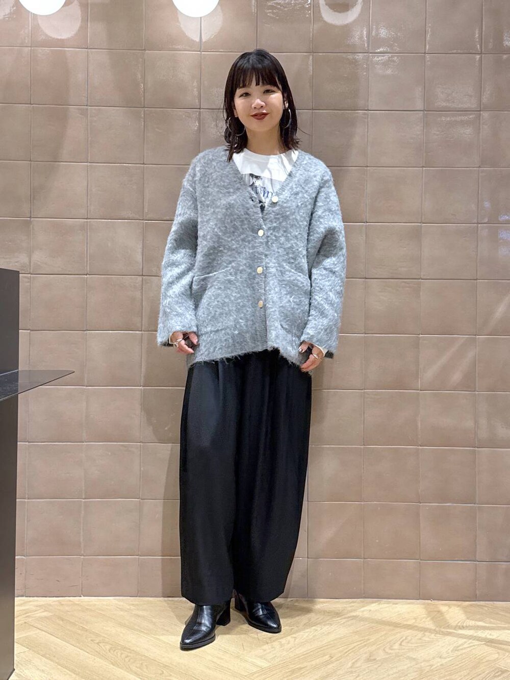 ブラック系のスラックス、グレー系のカーディガン/ボレロ、ホワイト系のTシャツ/カットソーを着用したレディースの冬コーディネートの2枚目の写真
