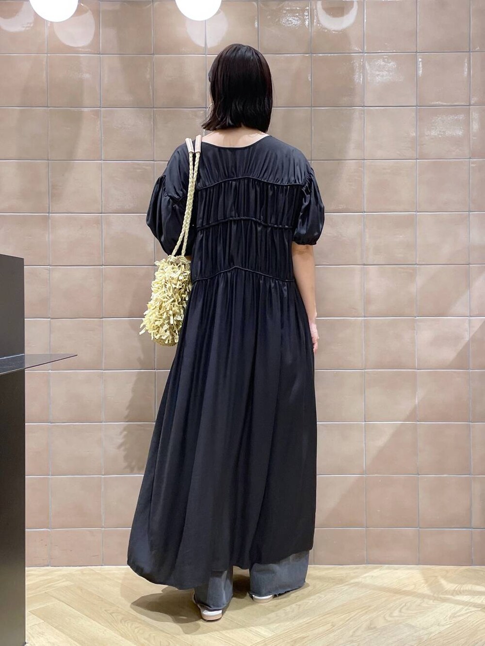 ベージュ系のトートバッグ、ホワイト系のサンダル、グレー系のデニムパンツを着用したレディースの夏コーディネートの3枚目の写真
