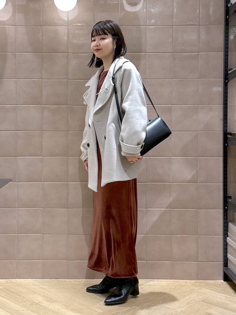 ベージュ系のピーコート、ブラック系のブーツ、ブラウン系のワンピースを着用したレディースの冬コーディネートの3枚目の写真