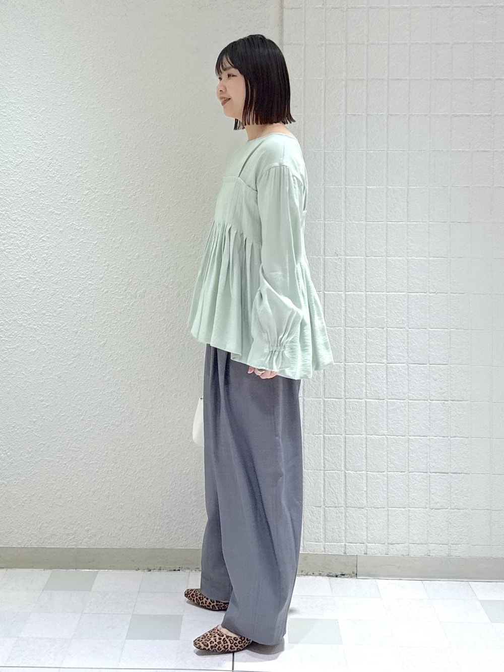 グレー系のスラックス、グリーン系のシャツ/ブラウス、ホワイト系のショルダーバッグを着用したレディースの冬コーディネートの5枚目の写真