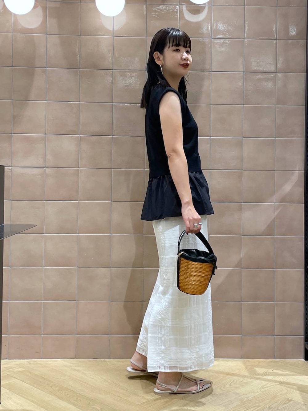 ブラック系のベスト、ブラック系のショルダーバッグ、ホワイト系のサンダルを着用したレディースの春コーディネートの2枚目の写真