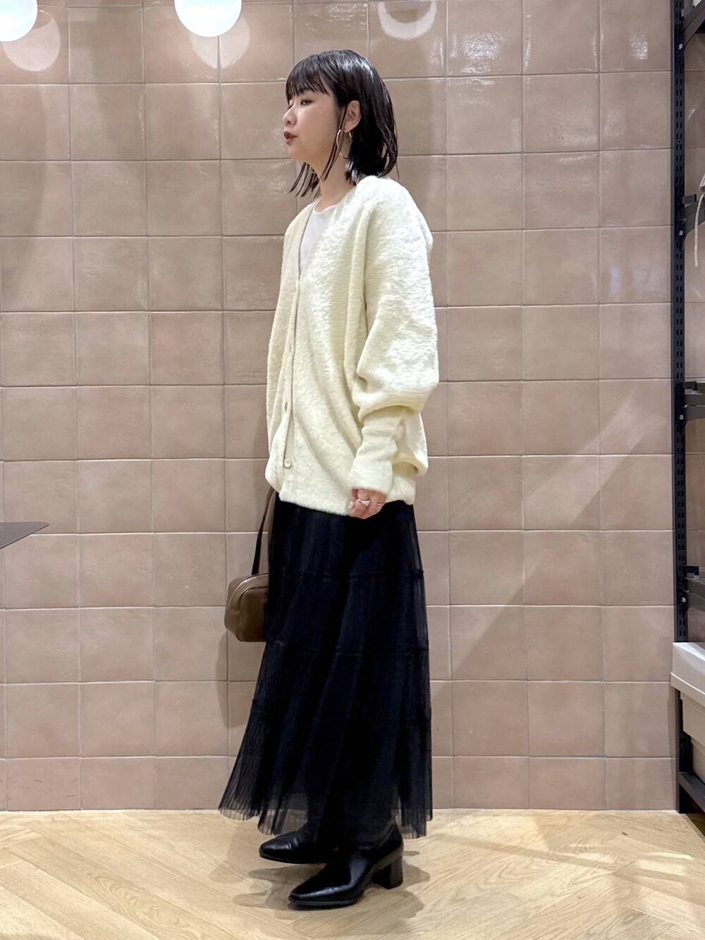 ホワイト系のTシャツ/カットソー、ブラック系のスカート、ベージュ系のカーディガン/ボレロを着用したレディースの冬コーディネートの3枚目の写真