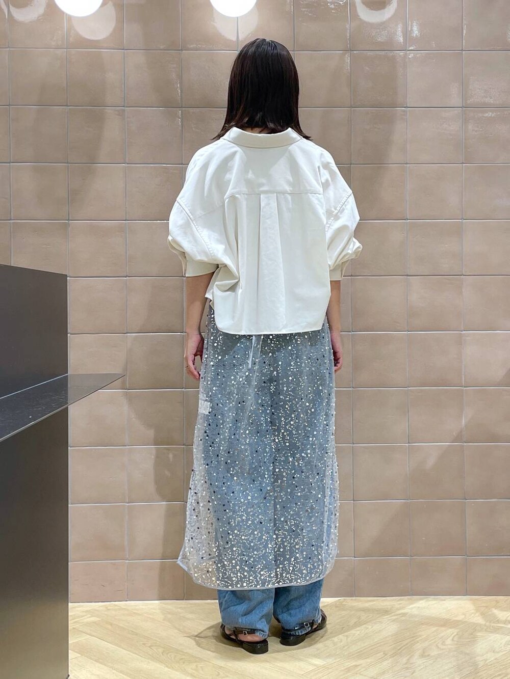 ブルー系のデニムパンツ、ブラック系のパンプス、グレー系のワンピースを着用したレディースの秋コーディネートの3枚目の写真