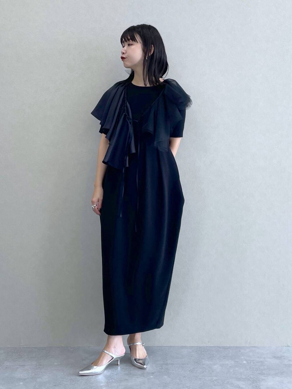 シルバー系のサンダル、グレー系のベスト、ブラック系のドレスを着用したレディースの冬コーディネートの5枚目の写真
