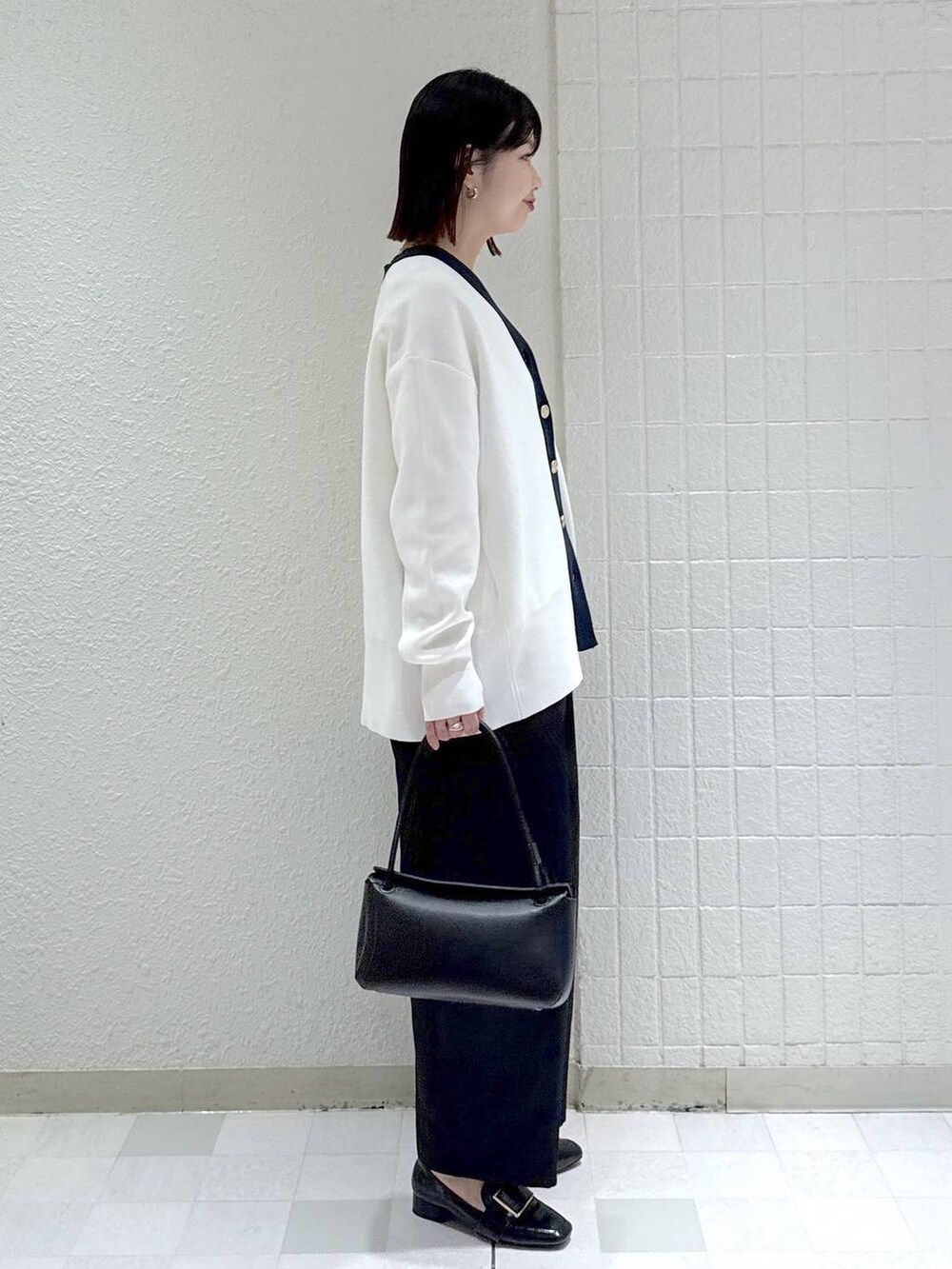 ブラック系のカーディガン/ボレロ、ホワイト系のタンクトップ、ブラック系のローファーを着用したレディースの冬コーディネートの2枚目の写真