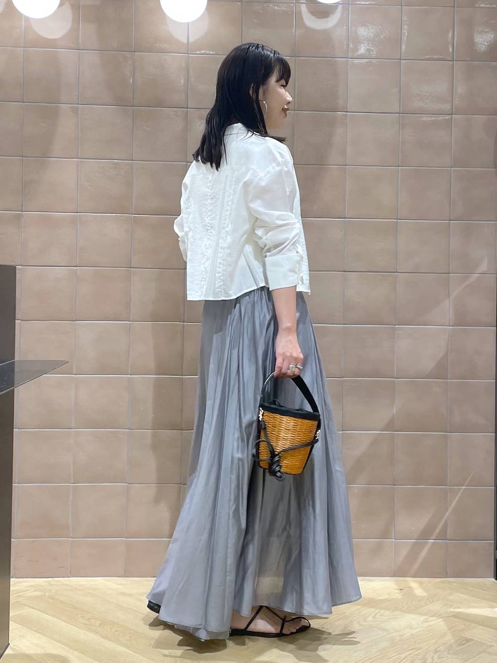 ホワイト系のタンクトップ、ブラック系のサンダル、グレー系のスカートを着用したレディースの春コーディネートの2枚目の写真