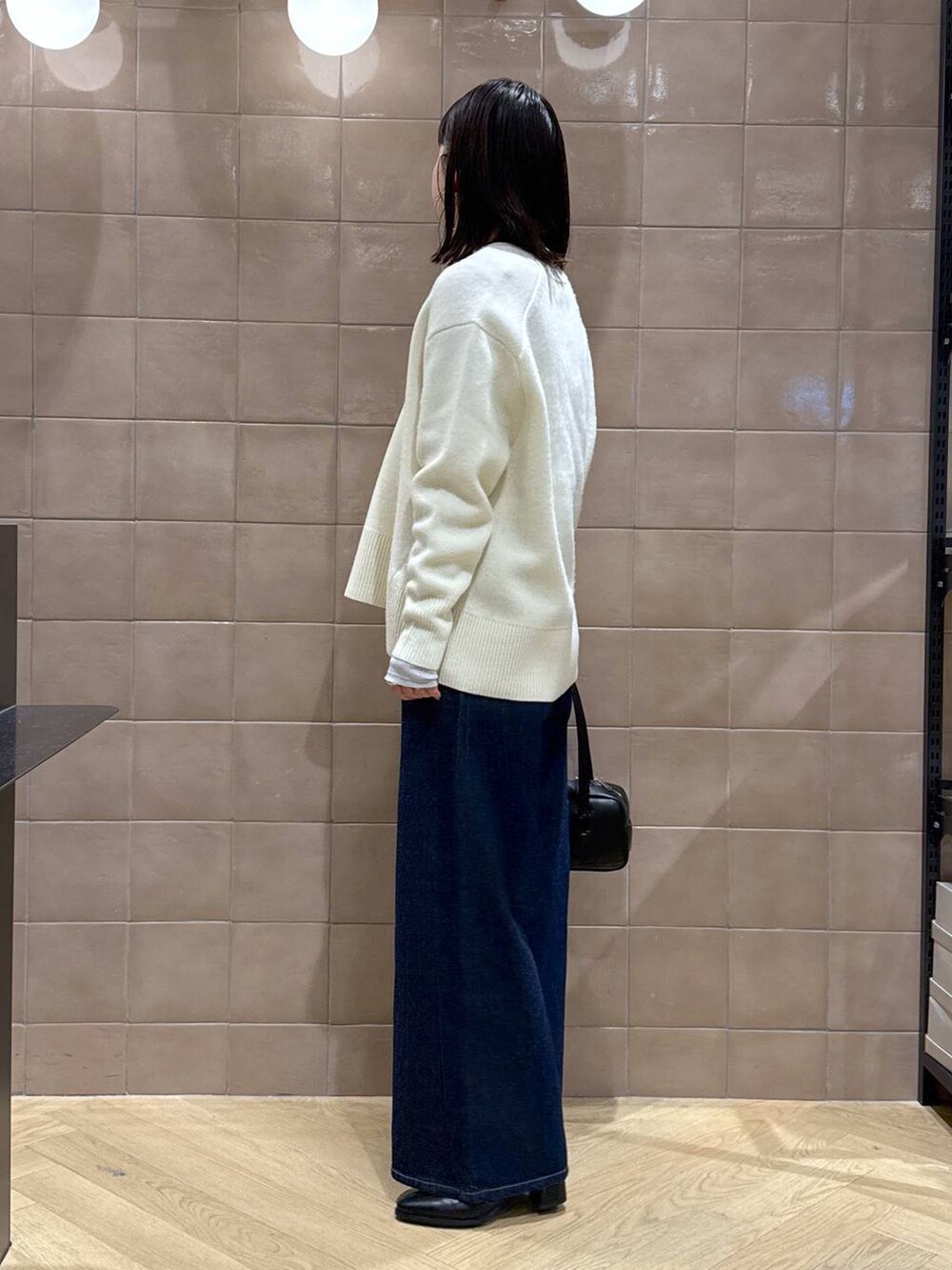 ホワイト系のニット/セーター、グレー系のTシャツ/カットソー、ブラック系のブーツを着用したレディースの冬コーディネートの5枚目の写真