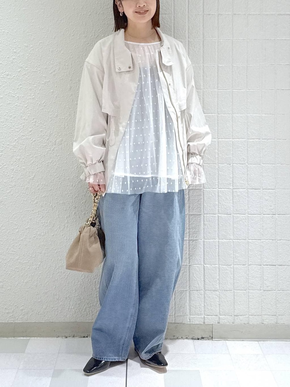 ブルー系のデニムパンツ、ベージュ系のブルゾン、ベージュ系のショルダーバッグを着用したレディースの春コーディネートの5枚目の写真