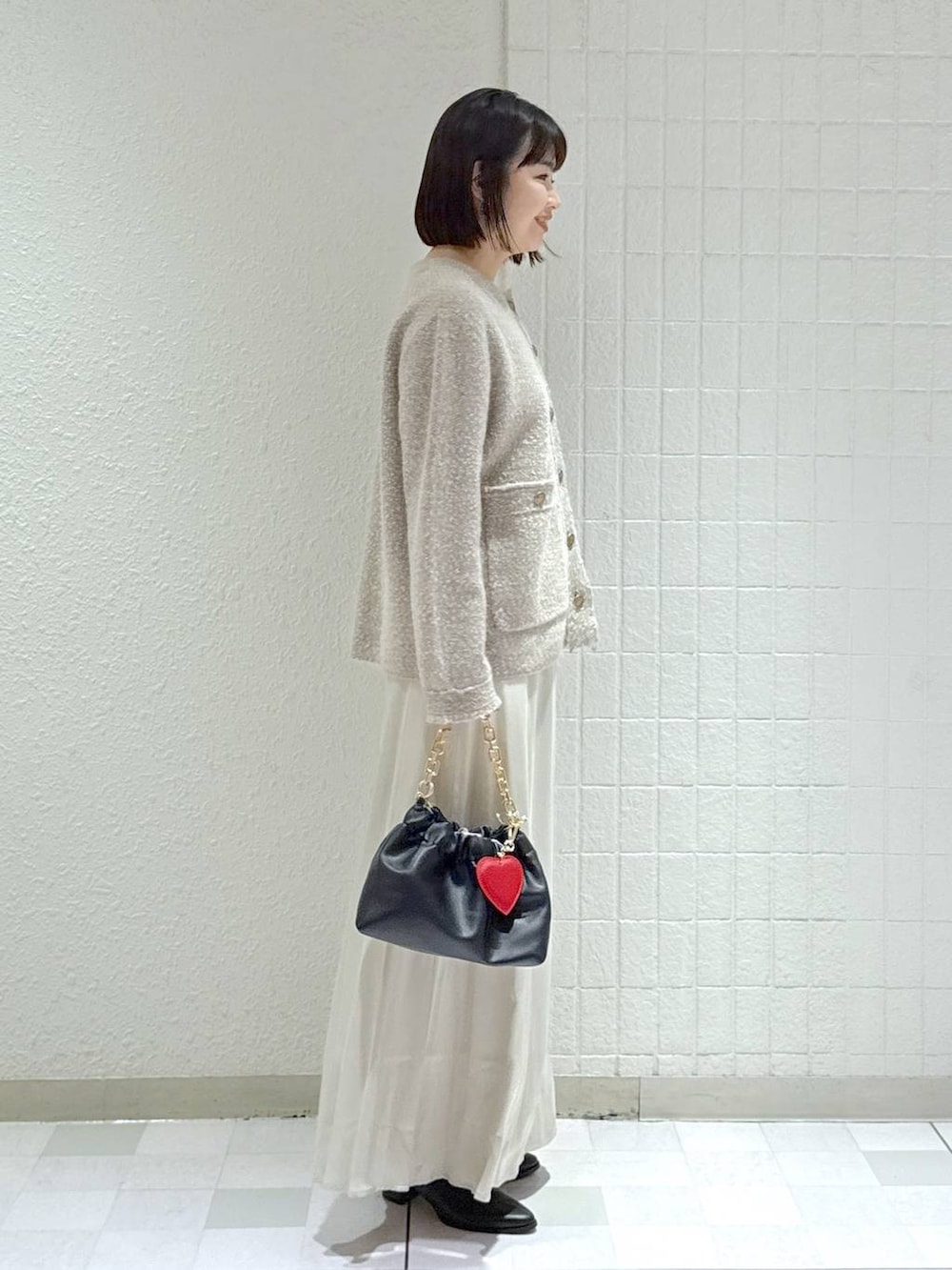 ブラック系のブーツ、ベージュ系のカーディガン/ボレロ、ブラック系のショルダーバッグを着用したレディースの秋コーディネートの3枚目の写真