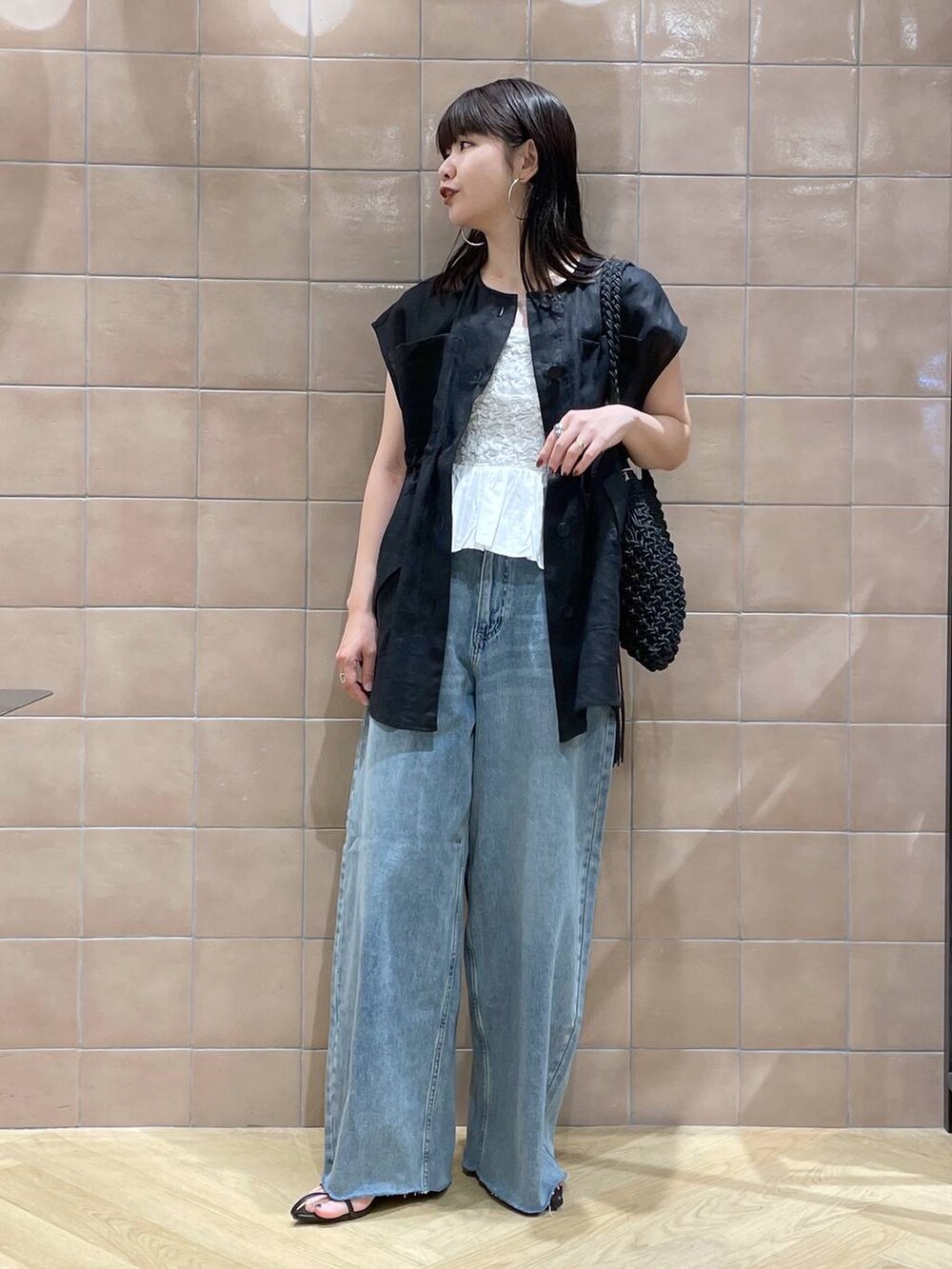 ブラック系のショルダーバッグ、ブラック系のベスト、ブラック系のサンダルを着用したレディースの春コーディネートの3枚目の写真