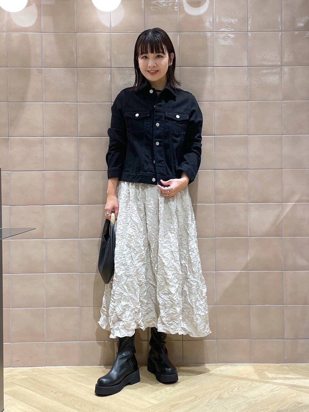 ブラック系のデニムジャケット、ブラック系のハンドバッグ、ブラック系のシャツ/ブラウスを着用したレディースの秋コーディネートの2枚目の写真