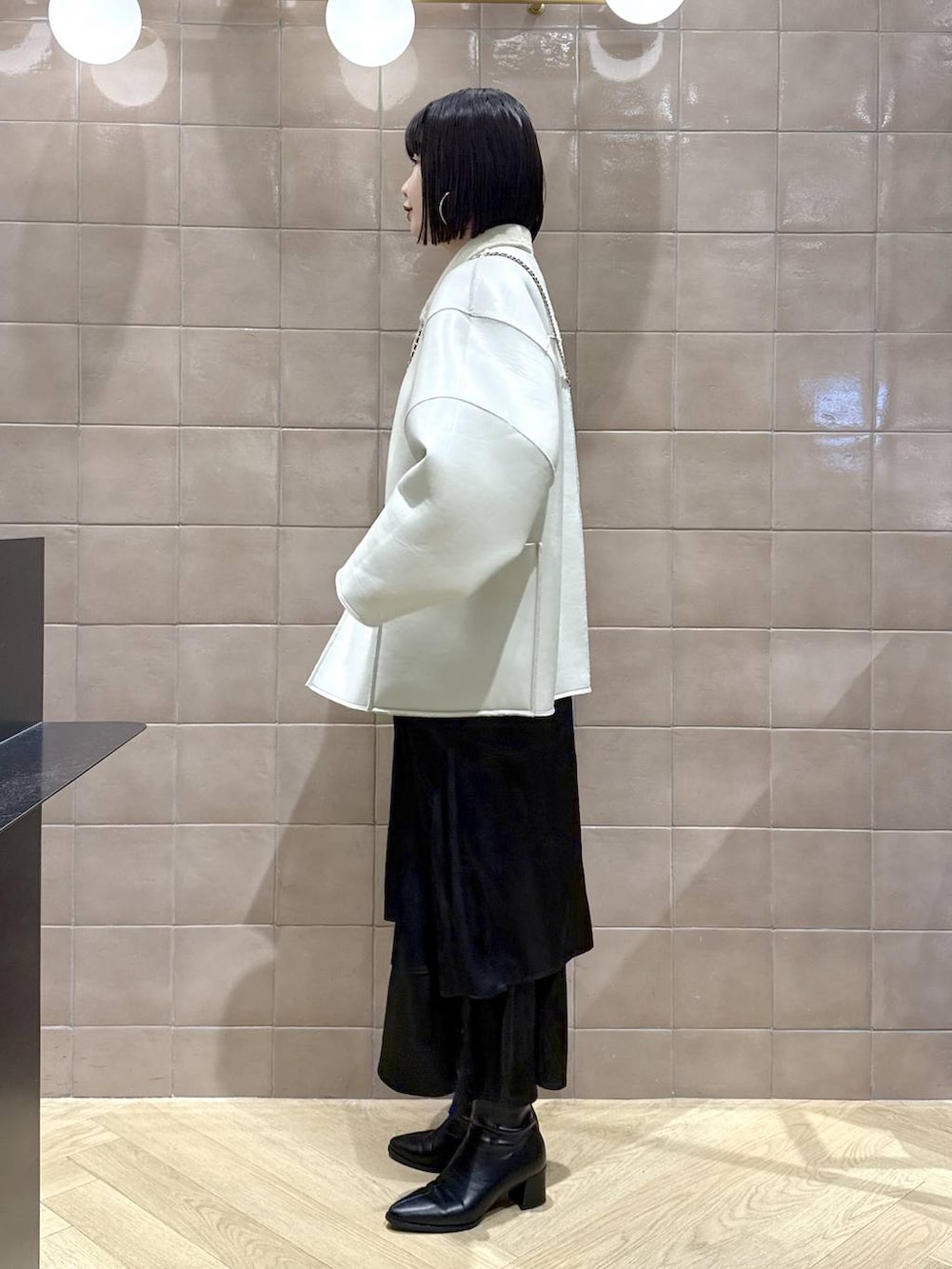 ブラック系のブーツ、ベージュ系のブルゾン、ブルー系のショルダーバッグを着用したレディースの秋コーディネートの3枚目の写真