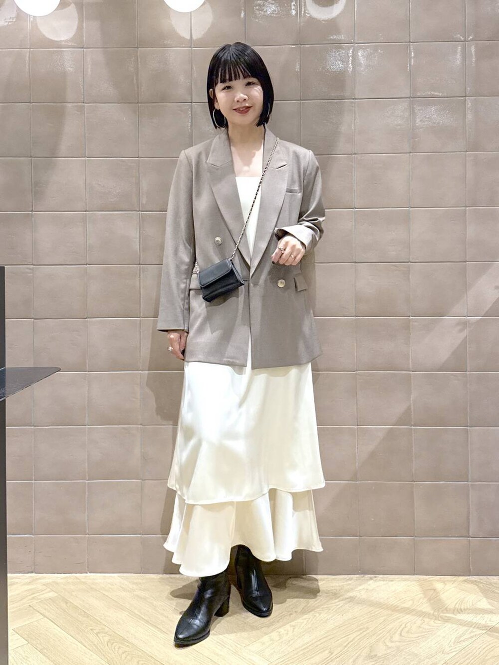 ブラック系のブーツ、グレー系のテーラードジャケット、ホワイト系のワンピースを着用したレディースの秋コーディネートの2枚目の写真