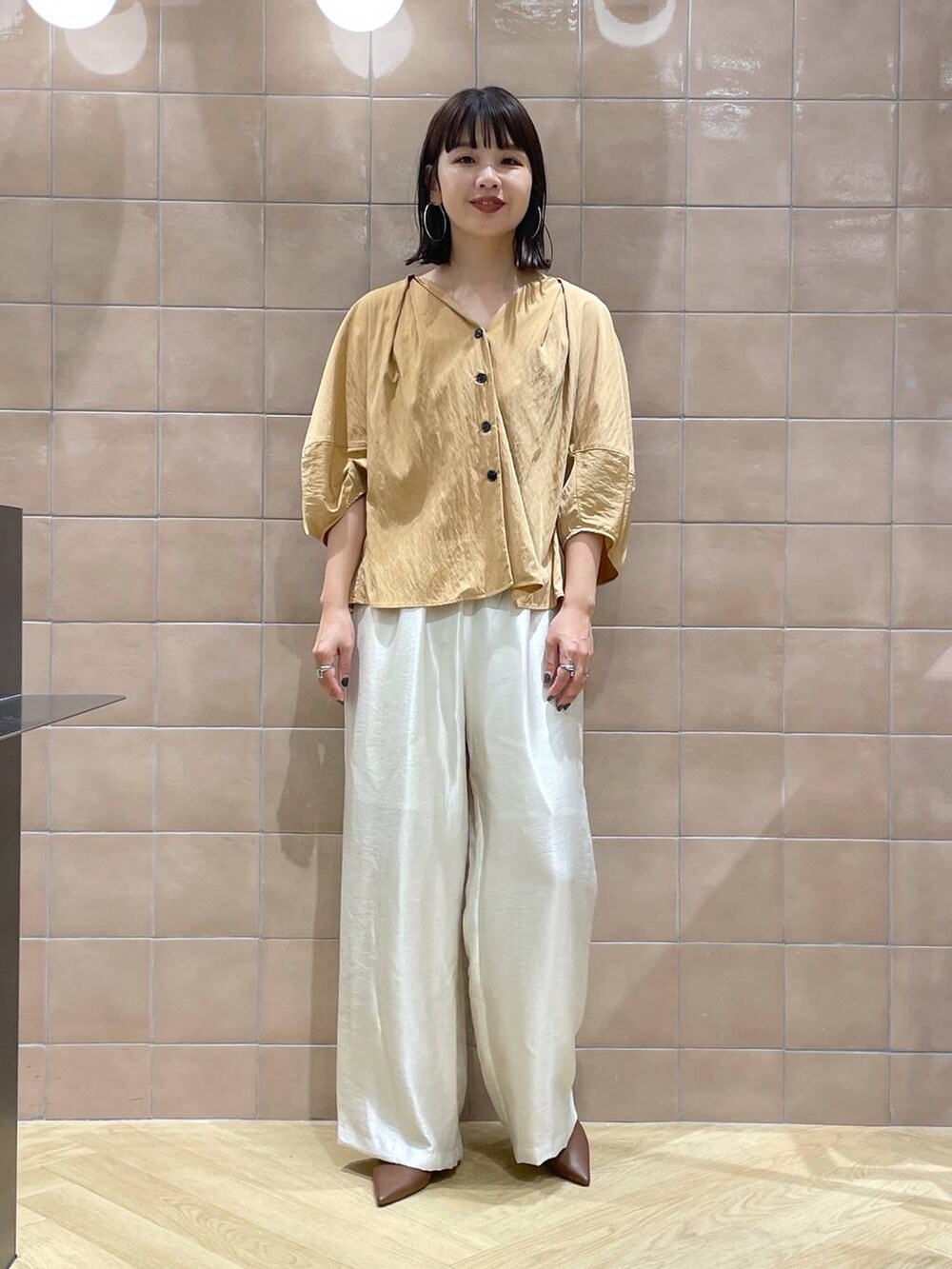 ブラウン系のパンプス、ホワイト系のその他パンツ、オレンジ系のシャツ/ブラウスを着用したレディースの夏コーディネートの3枚目の写真