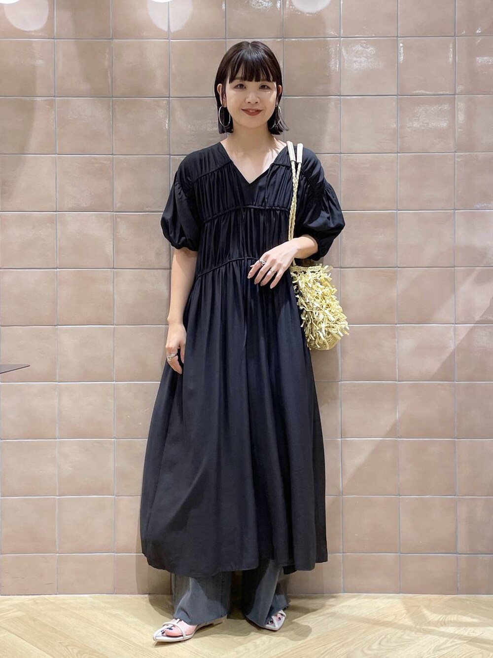 ベージュ系のトートバッグ、ホワイト系のサンダル、グレー系のデニムパンツを着用したレディースの夏コーディネートの2枚目の写真