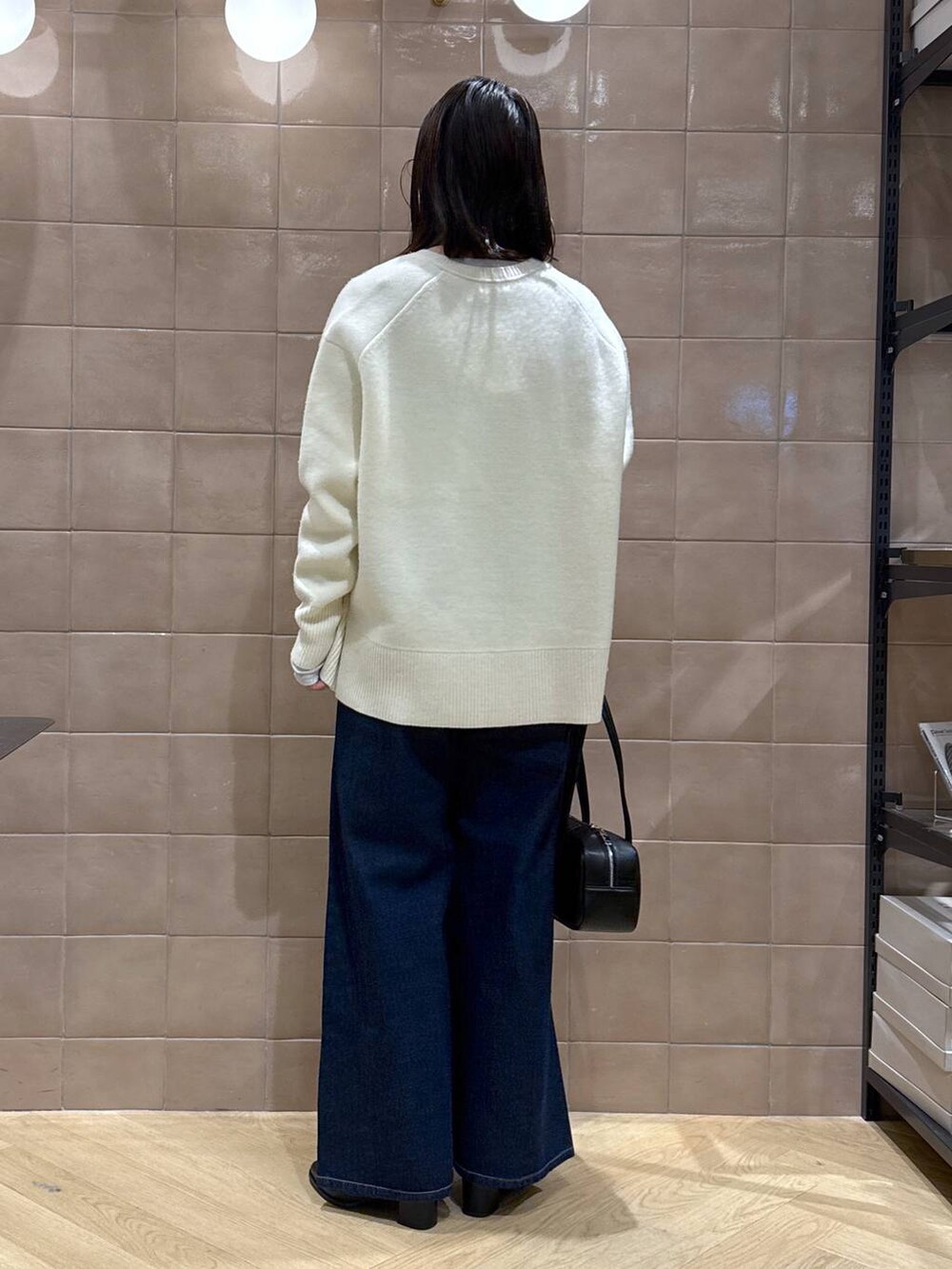 ホワイト系のニット/セーター、グレー系のTシャツ/カットソー、ブラック系のブーツを着用したレディースの冬コーディネートの4枚目の写真