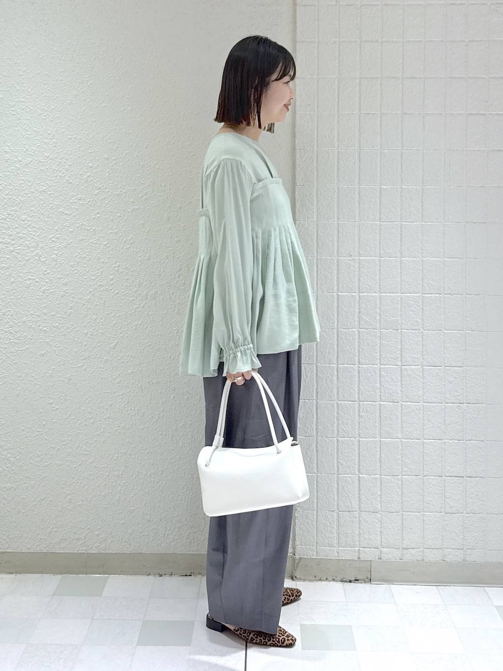 グレー系のスラックス、グリーン系のシャツ/ブラウス、ホワイト系のショルダーバッグを着用したレディースの冬コーディネートの3枚目の写真