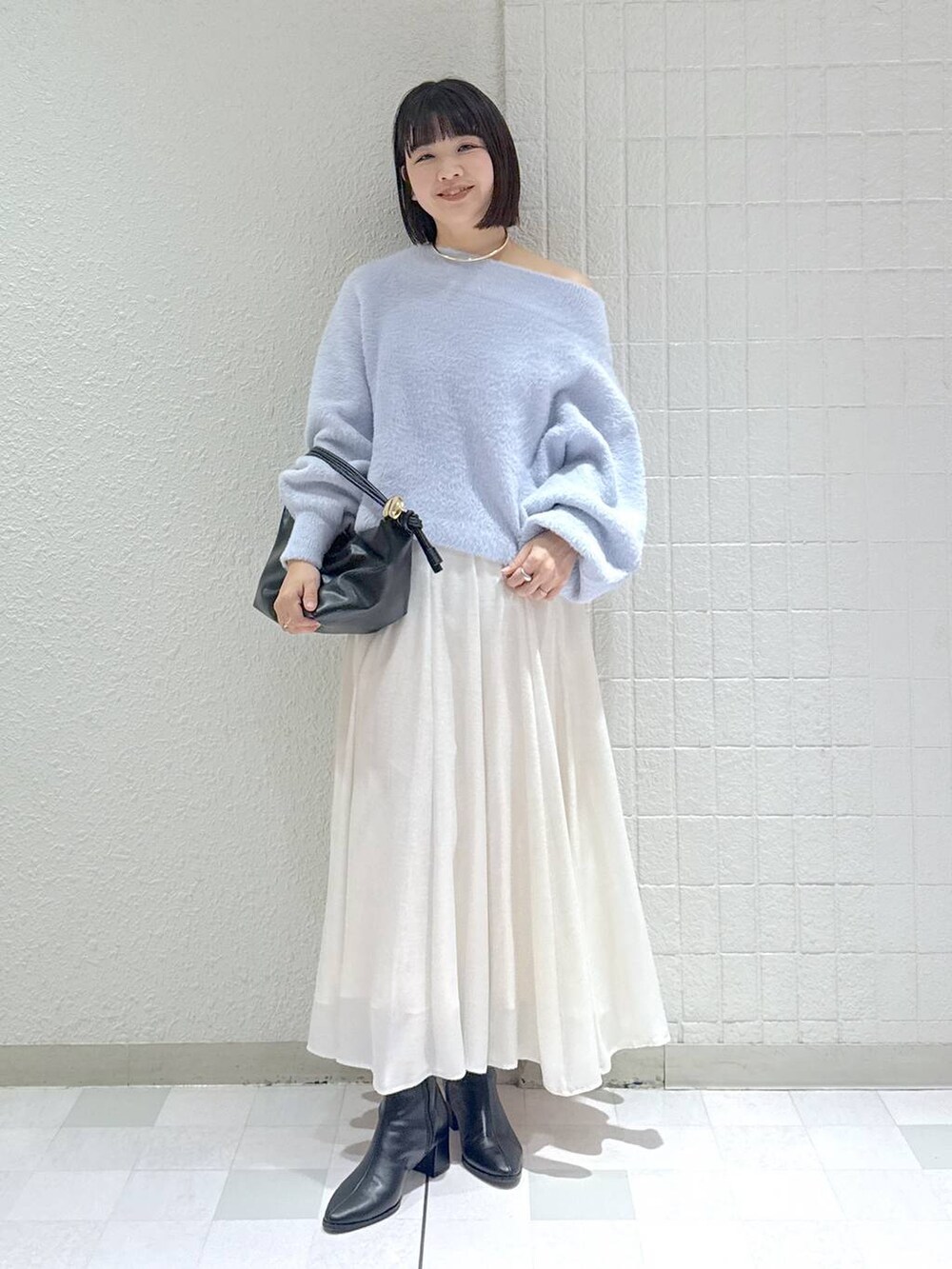 ブラック系のブーツ、ブラック系のショルダーバッグ、ブルー系のニット/セーターを着用したレディースの冬コーディネートの2枚目の写真