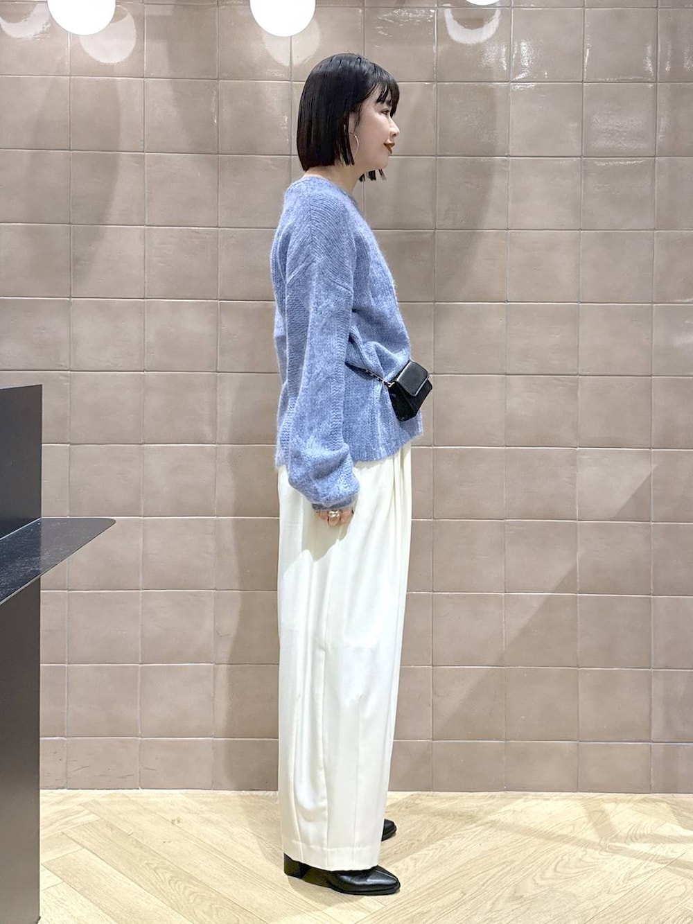 ホワイト系のスラックス、グレー系のTシャツ/カットソー、ブラック系のブーツを着用したレディースの秋コーディネートの2枚目の写真