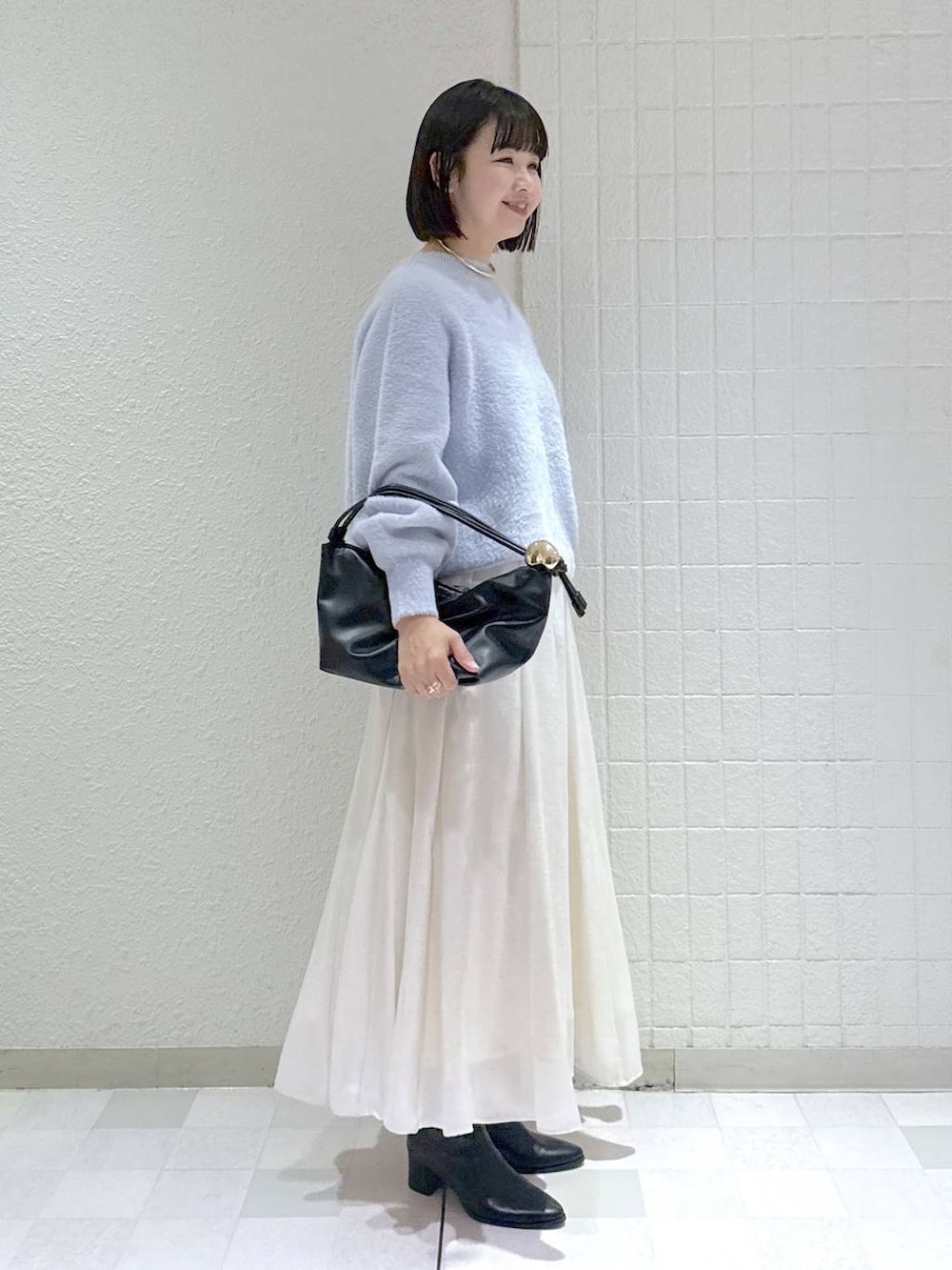 ブラック系のブーツ、ブラック系のショルダーバッグ、ブルー系のニット/セーターを着用したレディースの冬コーディネートの3枚目の写真