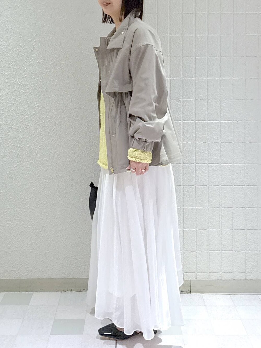 グレー系のブルゾン、ホワイト系のスカート、ブラック系のショルダーバッグを着用したレディースの春コーディネートの4枚目の写真