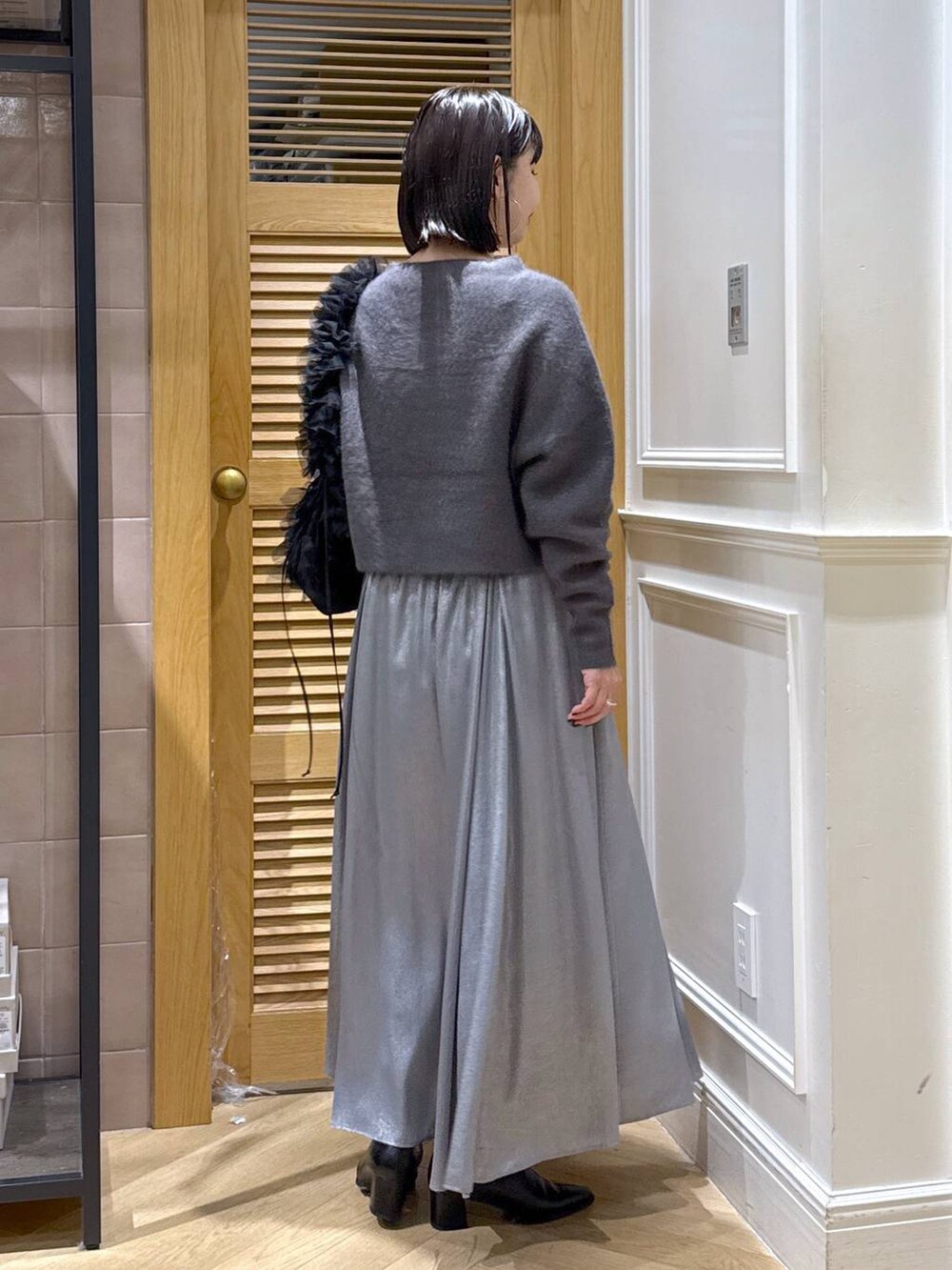 グレー系のニット/セーター、グレー系のスカート、ブラック系のショルダーバッグを着用したレディースの秋コーディネートの4枚目の写真