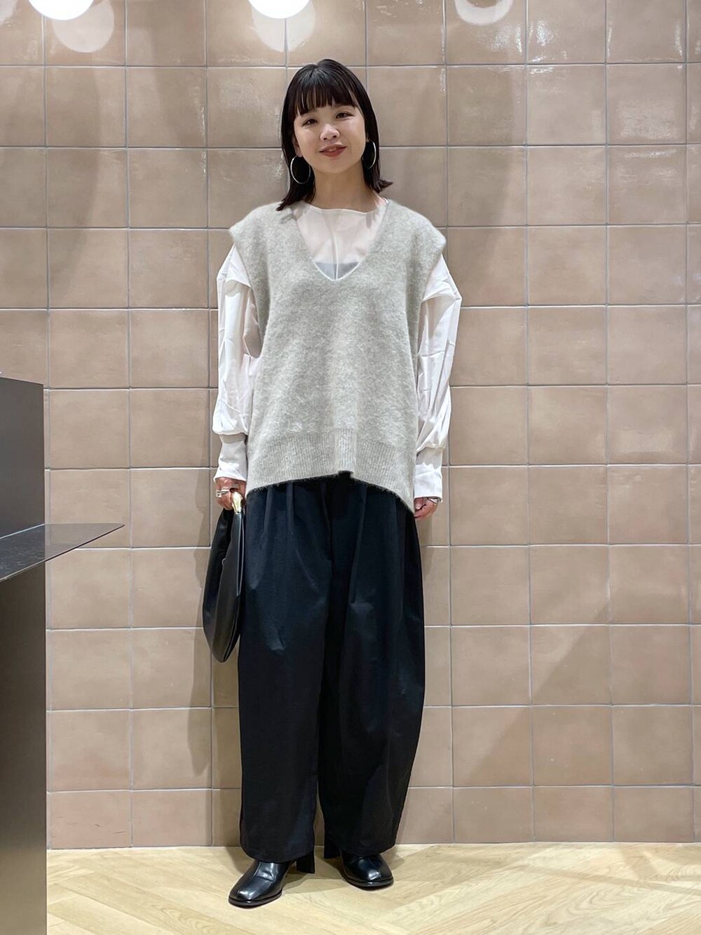 ブラック系のハンドバッグ、ベージュ系のベスト、ベージュ系のシャツ/ブラウスを着用したレディースの秋コーディネートの2枚目の写真