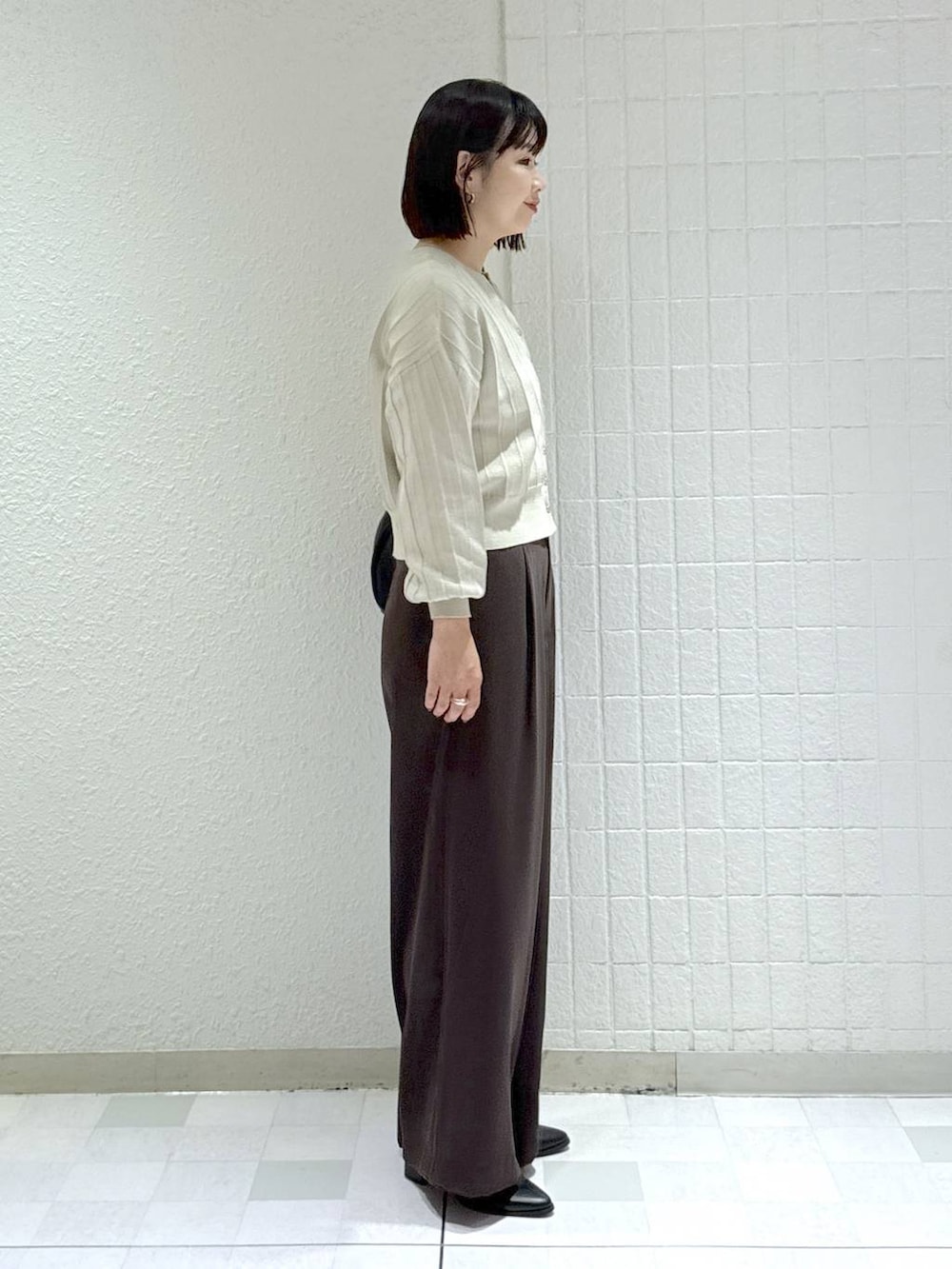 ブラック系のハンドバッグ、ベージュ系のカーディガン/ボレロ、ブラック系のブーツを着用したレディースの秋コーディネートの3枚目の写真