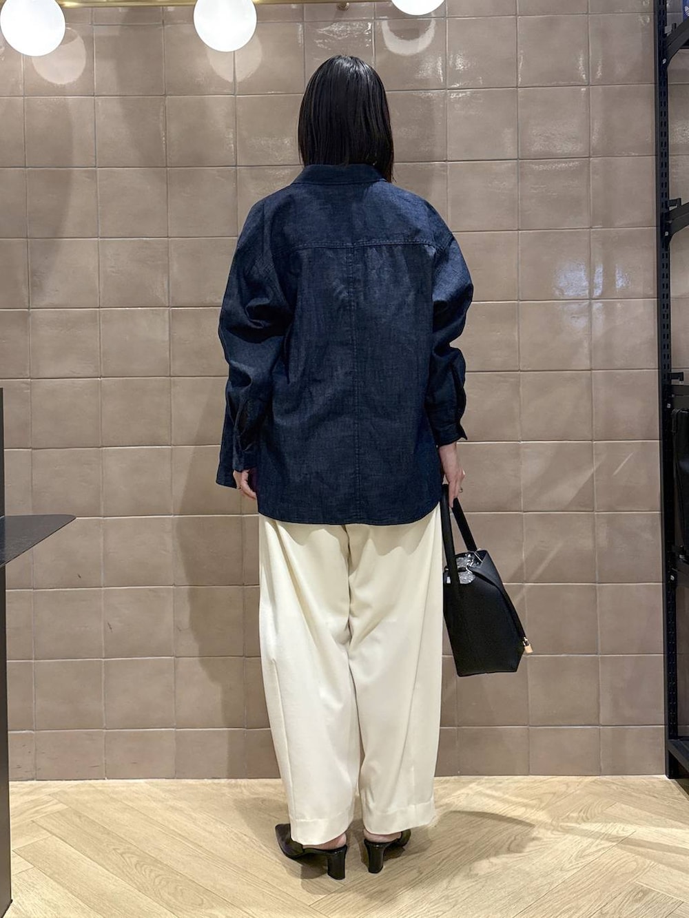 ホワイト系のスラックス、ブラック系のパンプス、ブラック系のショルダーバッグを着用したレディースの春コーディネートの5枚目の写真