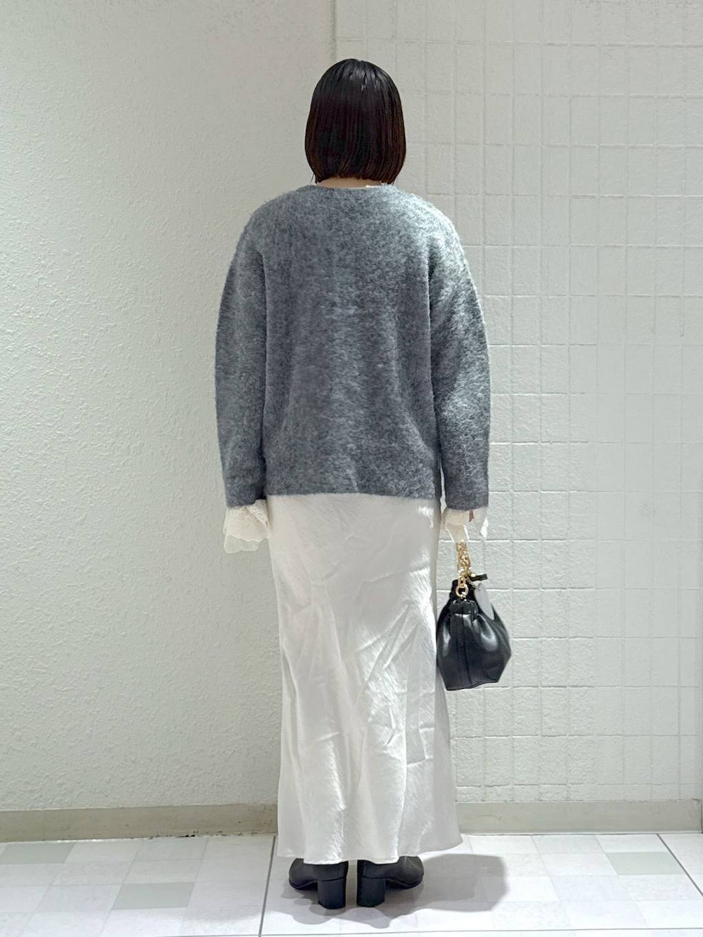 ブラック系のブーツ、グレー系のカーディガン/ボレロ、ホワイト系のスカートを着用したレディースの秋コーディネートの3枚目の写真