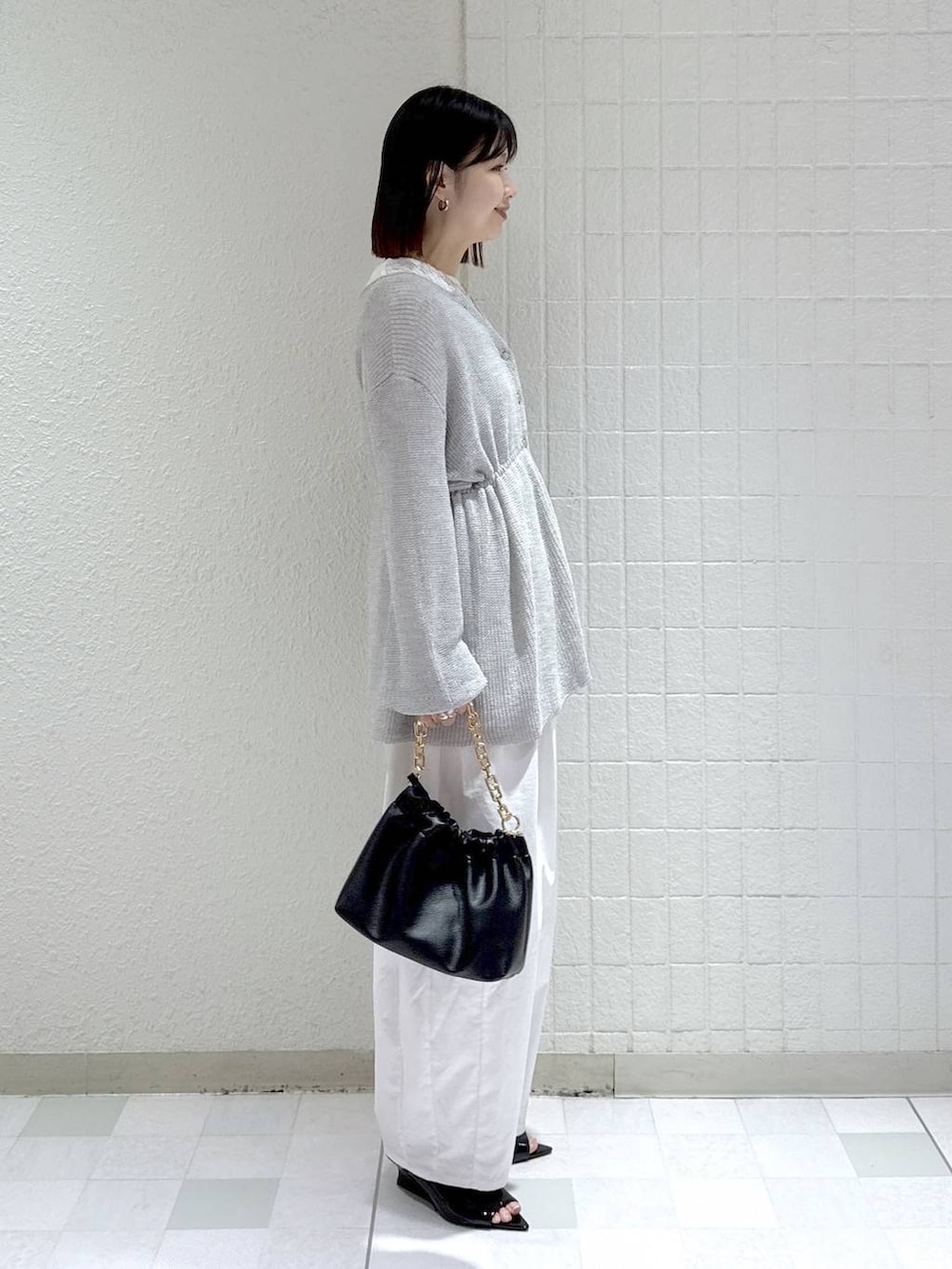 ホワイト系のTシャツ/カットソー、ブラック系のショルダーバッグ、グレー系のカーディガン/ボレロを着用したレディースの春コーディネートの2枚目の写真
