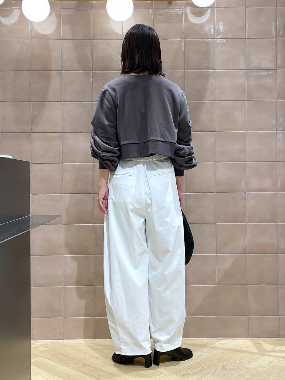 ブラック系のハンドバッグ、ブラック系のサンダル、ホワイト系のその他パンツを着用したレディースの秋コーディネートの2枚目の写真