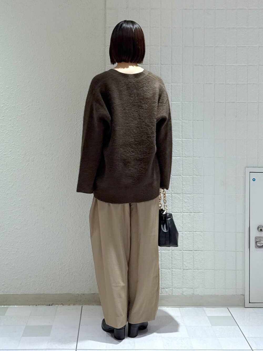 ブラウン系のカーディガン/ボレロ、ベージュ系のスラックス、ブラック系のブーツを着用したレディースの秋コーディネートの4枚目の写真