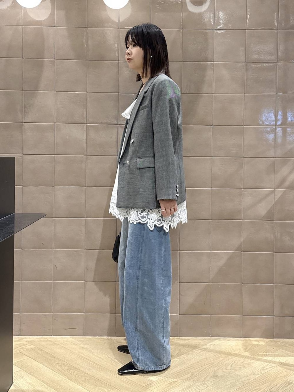 ブルー系のデニムパンツ、ブラック系のテーラードジャケット、ホワイト系のキャミソールを着用したレディースの春コーディネートの4枚目の写真