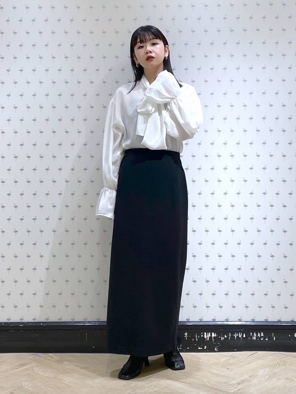 ブラック系のショルダーバッグ、ブラック系のブーツ、ブラック系のスカートを着用したレディースの冬コーディネートの5枚目の写真