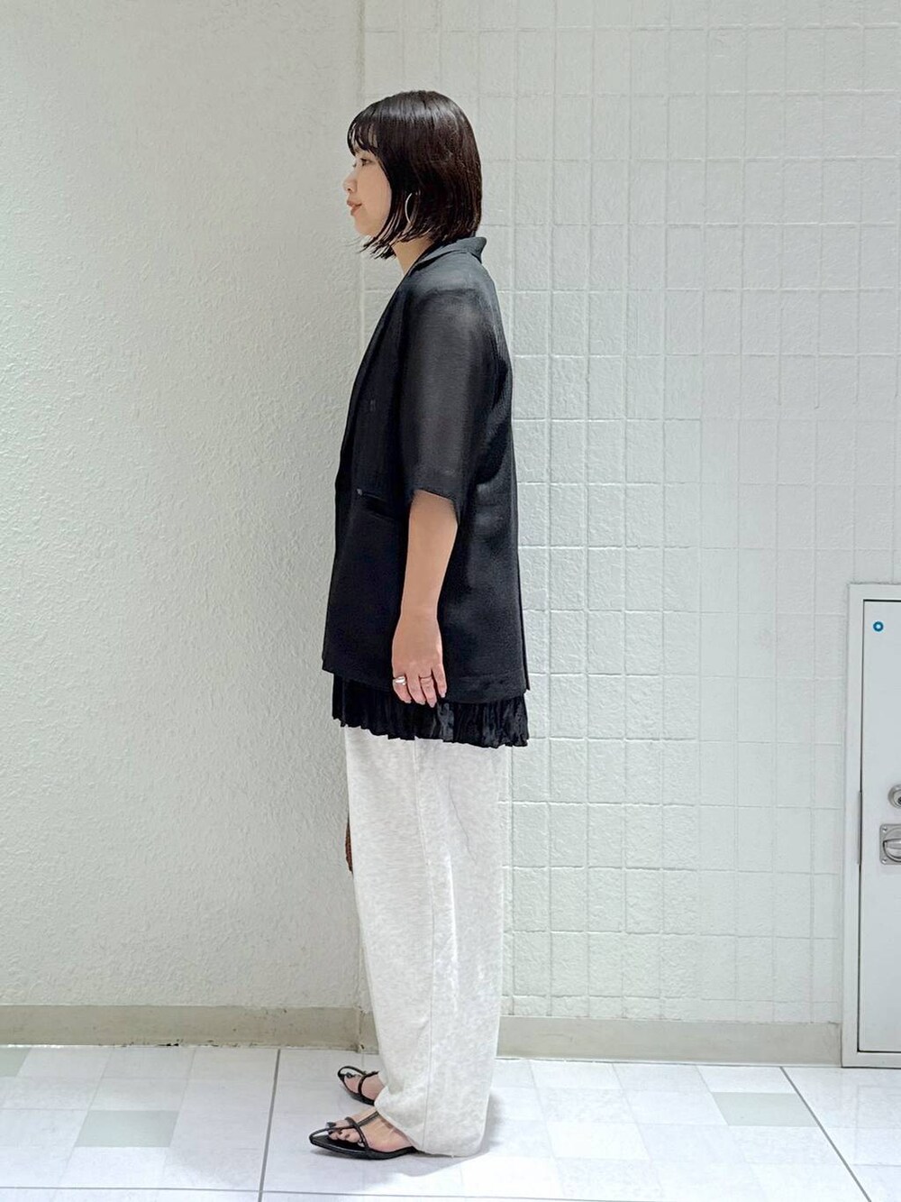 ブラック系のサンダル、ブラウン系のハンドバッグ、グレー系のスウェットパンツを着用したレディースの夏コーディネートの4枚目の写真