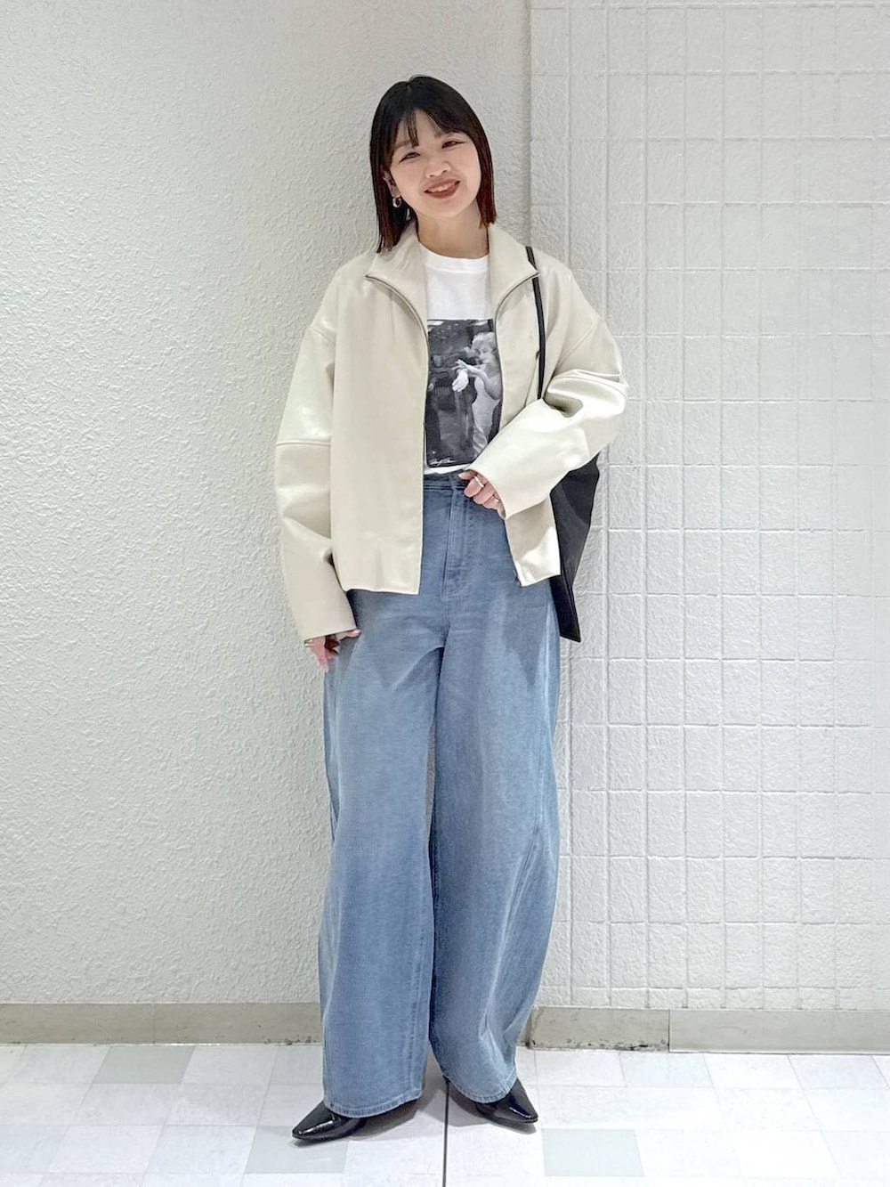 ブルー系のデニムパンツ、ホワイト系のブルゾン、ブラック系のパンプスを着用したレディースの春コーディネートの2枚目の写真