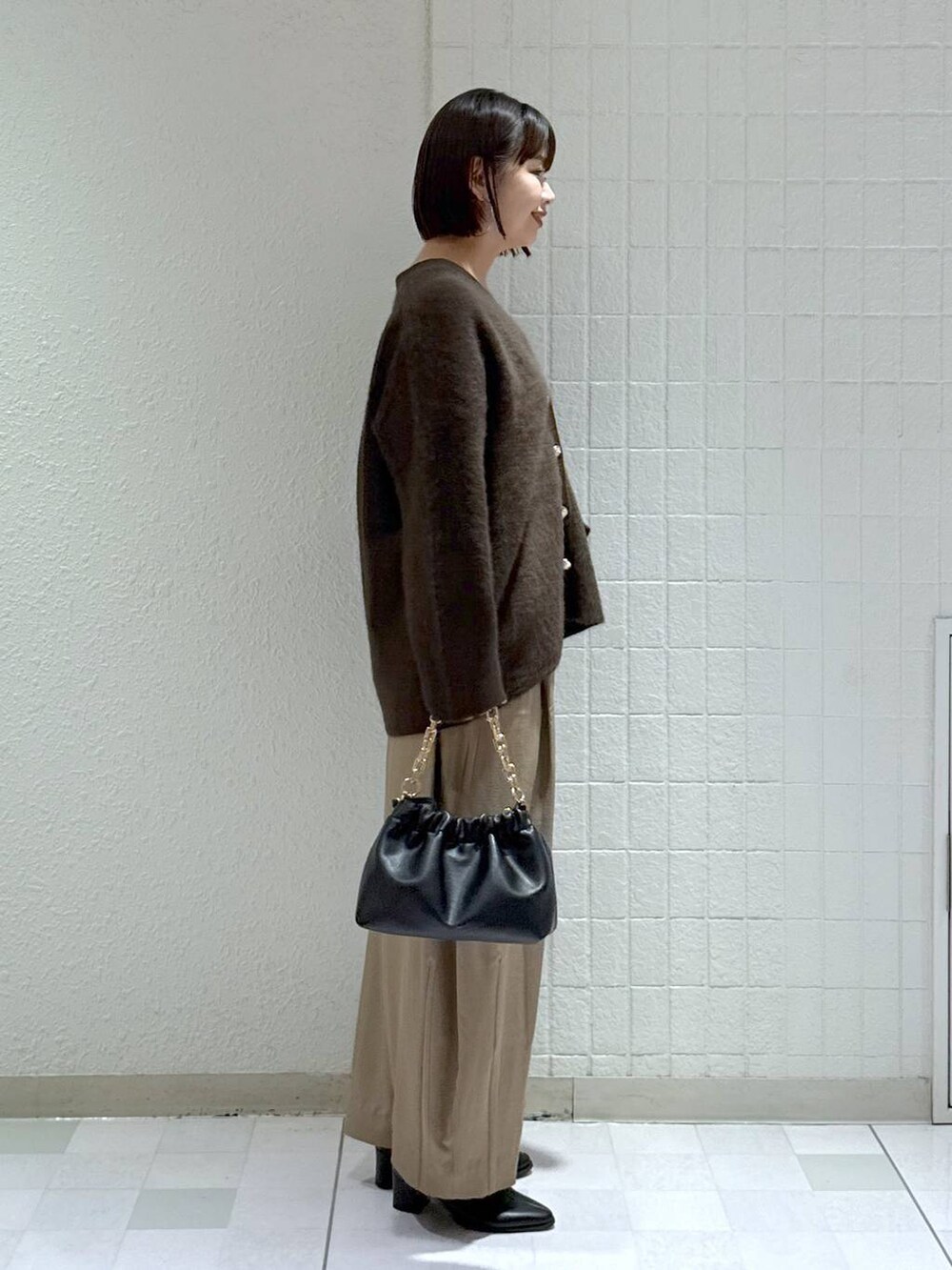 ブラウン系のカーディガン/ボレロ、ベージュ系のスラックス、ブラック系のブーツを着用したレディースの秋コーディネートの3枚目の写真