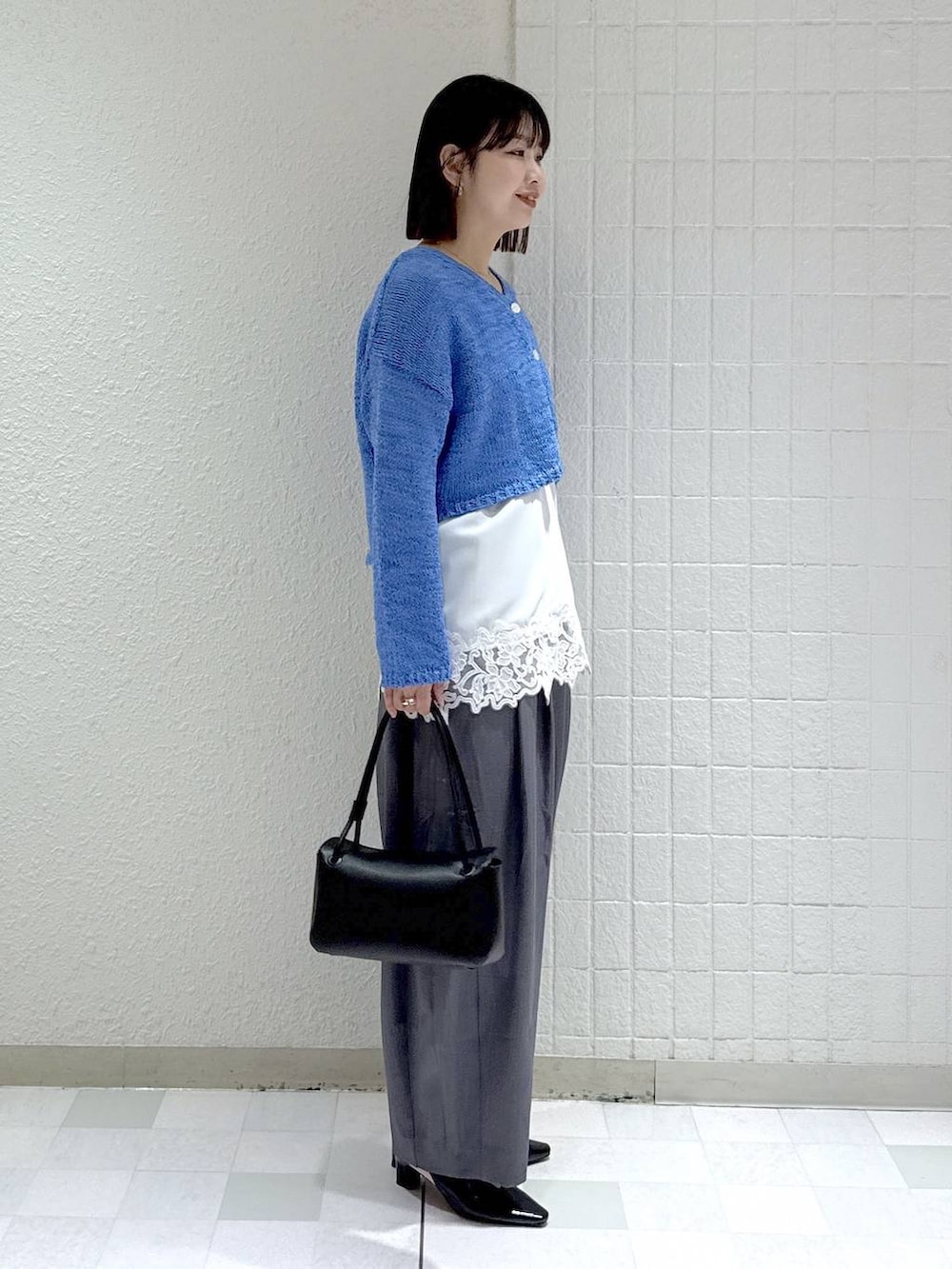 グレー系のスラックス、ホワイト系のキャミソール、ブラック系のパンプスを着用したレディースの春コーディネートの3枚目の写真