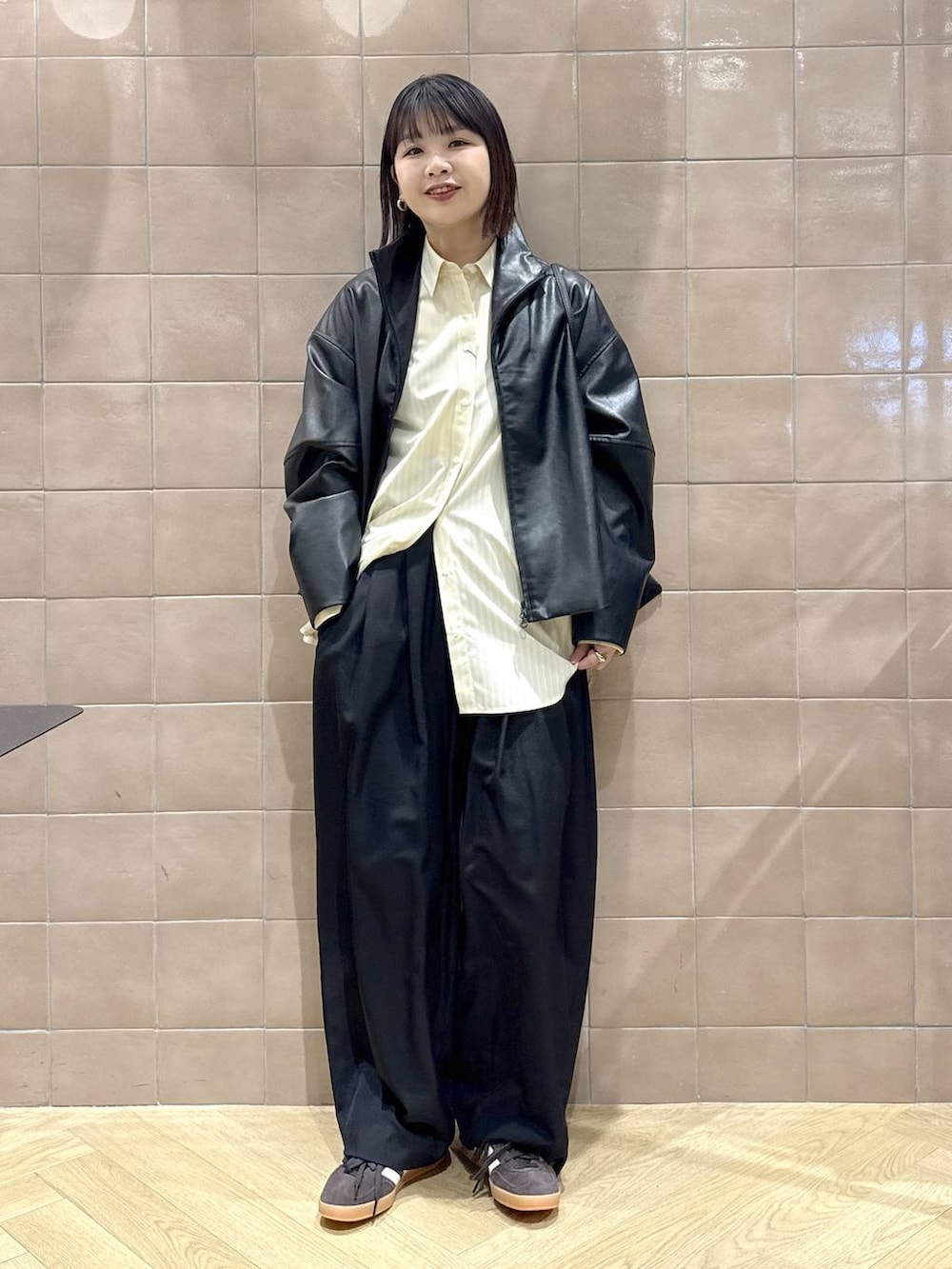 ブラック系のスラックス、ブラック系のブルゾン、イエロー系のシャツ/ブラウスを着用したレディースの冬コーディネートの2枚目の写真